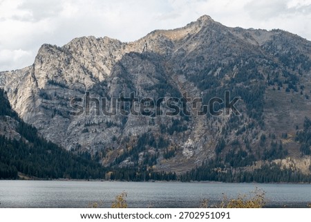 The rugged cliffs and tree lined lower slopes of Prospectors Mountain reflected in the waters of Phelps Lake in Grand Teton National Park 