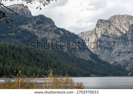 The rugged cliffs and tree lined lower slopes of Prospectors Mountain and  the waters of Phelps Lake in Grand Teton National Park 