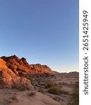 Rugged desert landscape with reddish rock formations at golden hour in Wadi Rum, Jordan.