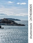 The rugged Marseille waterfront unfolds in this striking photo, showcasing a weathered concrete pier jutting out into the vast Mediterranean Sea.