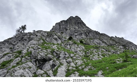 A rugged mountain landscape with rocky terrain and patches of green vegetation under a cloudy sky. - Powered by Shutterstock