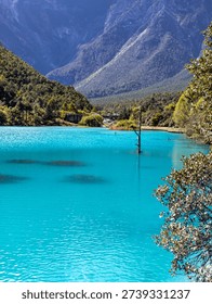 Rugged mountain peaks seen through the trees above the turquoise waters of Blue Moon Valley in Yunnan.