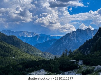 Rugged mountain peaks under dramatic clouds in alpine valley landscape