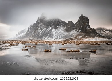 Rugged mountain reflected in shallow pool under threatening sky