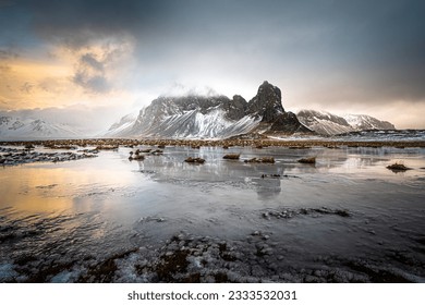 Rugged mountain reflected in shallow pool under threatening sky