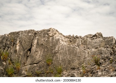 Rugged mountain side composed of massive rocks, with cloudy sky in the background