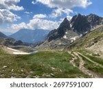 Rugged Pyrenees mountains defining a path leading to a small alpine lake in Naut Aran, Catalonia