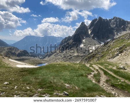 Rugged Pyrenees mountains defining a path leading to a small alpine lake in Naut Aran, Catalonia