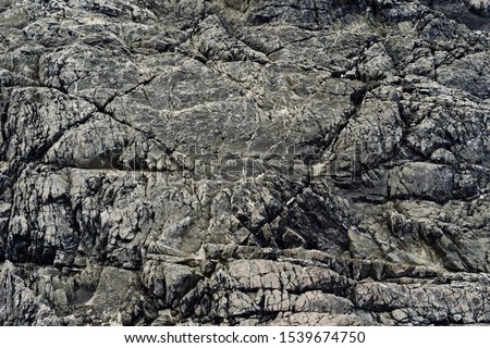 Rugged rock background - dark bedrock with many cracks and crevices - greys and blacks color - Tofino, Vancouver Island, BC, Canada