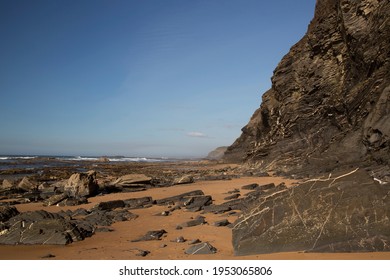 rugged rocky beach coastline with high cliffs and stunning views of the ocean and rock erosion on the beach at low tide - Powered by Shutterstock