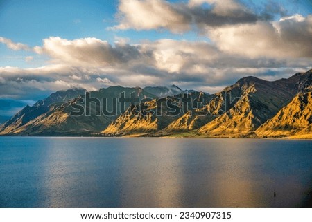 Rugged tall mountain range and lake side scenery around the shores of alpine Lake Hawea