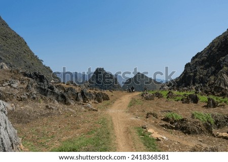 A rugged trail meandering through a mountainous terrain under a clear blue sky