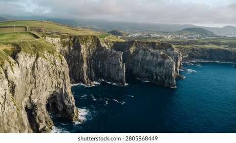 Rugged volcanic cliffs and green fields defining the dramatic coastline of são miguel, azores