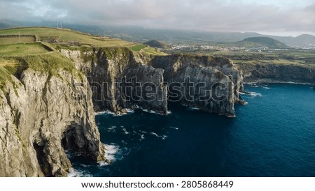 Rugged volcanic cliffs and green fields defining the dramatic coastline of são miguel, azores