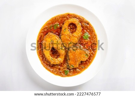 Ruhu rui or Katla  Fish curry, traditional bangali fish curry ,arranged in a white ceramic bowl garnished with fresh red chilly and curry leaves on a grey textured background,isolated, top view.