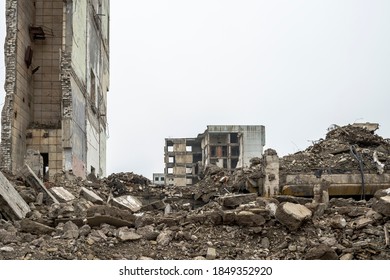 A ruined building with a pile of concrete gray debris against a neutral gray sky in a hazy haze. Background.