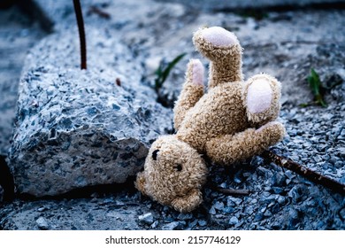 Ruined children's lives as a result of Russian aggression, loss childhood and future. Children's toy teddy bear lies on broken construction  debris against the background of destroyed building.