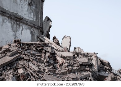 A ruined concrete building with a pile of rubble in the foreground against a gray sky background. Background.