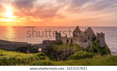 Ruined medieval Dunluce Castle on the cliff at amazing sunset, Wild Atlantic Way, Bushmills, County Antrim, Northern Ireland. Filming location of popular TV show, Game of Thrones, Castle Greyjoy
