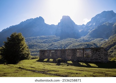 Ruined stone building on alpine meadow with view of majestic mountain massif Zhaborret, Albanian Alps (Accursed Mountains), Valbone Valley National Park, Albania. Scenic hiking trail Valbona to Theth - Powered by Shutterstock