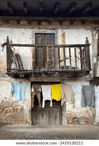 a ruined village house with a wooden balcony, with a clothesline, laundry in a rural environment, concept of depopulation of rural areas, exodus to the big cities, vertical