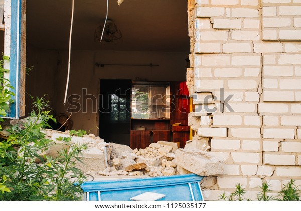 Ruined\
wall of the house. Hit a military projectile after a car accident.\
Destruction and earthquake. Migration and crisis. The brick house\
is destroyed. The window and the wall are\
broken.