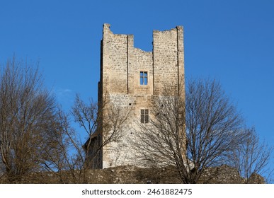 Ruins of abandoned old stone medieval town castle guard tower with broken windows on top of small hill surrounded with trees without leaves on clear blue sky background - Powered by Shutterstock