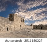 Ruins of Azraq Castle (Qasr al-Azraq) is a crusader castle (300AD),  central-eastern Jordan, 100 km east of Amman, Jordan. Against the background of a beautiful sky with clouds    