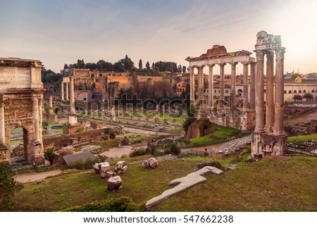 Ruins and columns of Roman Forum in warm light of sunset in Rome, Italy. Popular touristic destination and site. Ruins of Temple of Saturn. Temple of Saturn and Arch of Septimus Severus.