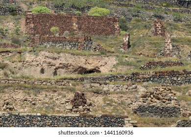 The Ruins Of Old Stone Houses On The Steep Slopes Of The Mountains. Outskirts. Long Focus Lens. Blurred Foreground. Santa Cruz De Tenerife, Canary Islands, Spain.