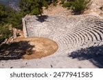 Ruins of Roman theater located on hillside in ancient settlement of Arykanda in Antalya province of Turkey. View of stone seats of semicircle auditorium descending towards ruined stage