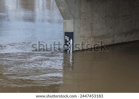 A ruler for measuring the water level of the Chagan River under the bridge. Rising water level. River water level. River level rise.