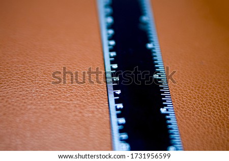 The ruler used in the Mathmatics class on the leather background.