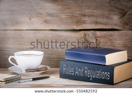 Rules And Regulations. Stack of books on wooden desk