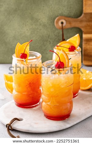 Rum punch in tiki glasses garnished with orange slices and a cherry
