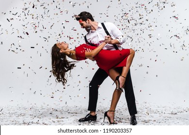 Rumba Time. Full Length Of Young Beautiful Couple Dancing While Standing Against White Background With Confetti 