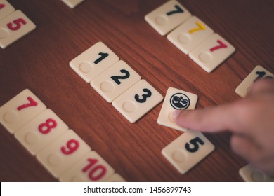 Rummikub board game tiles in a woodden table. Joker tile wildcard is selected. Iconic symbol of opportunity, second chance, possibility, cunning, hability, trickery, cleverness, astuteness, archness.
