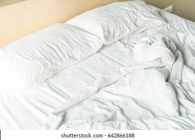 rumpled bed with white messy pillow decoration in bedroom interior