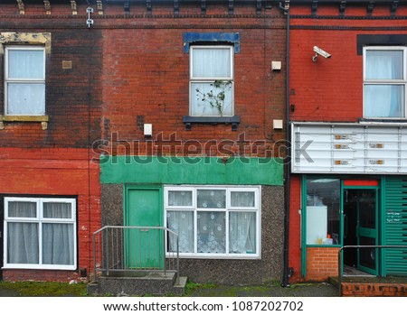run down terraced houses on a street in leeds with shabby decaying colourful painted walls and a shop front with an open door