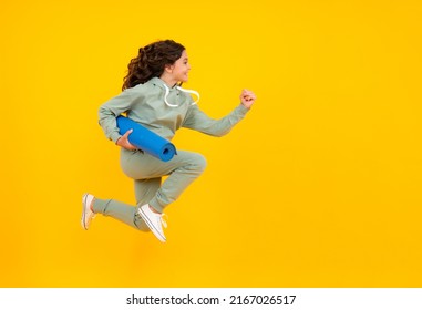 Run And Jump. Sportswear Advertising Concept. Teenager Child Girl In Tracksuits Jogging Suit Posing In The Studio Hold Fitness Mat.