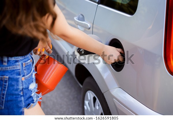 Run out of\
fuel in the middle of nowhere. Attractive girl is going to fill\
tank of modern car in the\
countryside