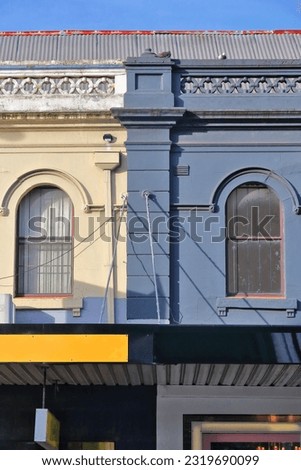 Run of Victorian commercial terraces with balustrade parapet, pitched sheet metal roof, and cantilevered awnings over the footpath frontshops of Oxford Street, Paddington suburb. Sydney-NSW-Australia.