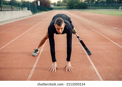 A Runner With Artificial Leg In Start Position At Stadium On Running Track.