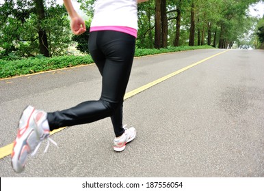 runner athlete feet running on road. woman fitness jogging workout wellness concept 