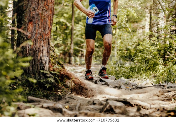 runner athlete running on forest trail water bottle\
in hand