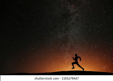 Runner Athlete Running On The Hill With Beautiful Starry Night Background. Silhouette Of Man Jogging Workout In Dark Time, Wellness Concept.