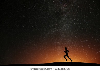 Runner Athlete Running On The Hill With Beautiful Starry Night Background. Silhouette Of Man Jogging Workout In Dark Time, Wellness Concept.