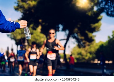 Runner Collects A Bottle Of Water To Hydrate During A Workout.