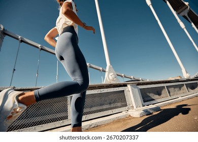 Runner exercising on a bridge under a clear blue sky