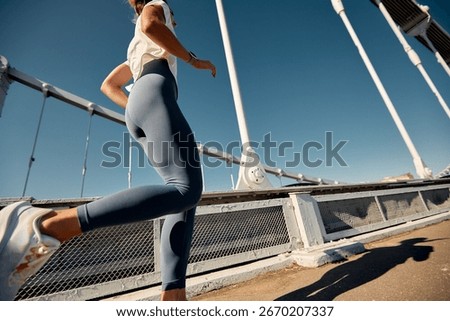 Runner exercising on a bridge under a clear blue sky